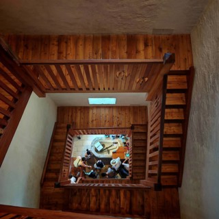 Wooden staircase looking down at a group of people gathered on the ground floor, Piran, Slovenia