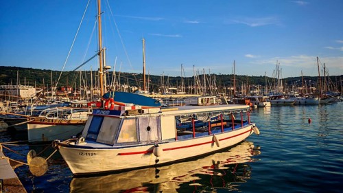 A small motor boat in the marina with numerous sailboats in the background, Izola, Slovenia