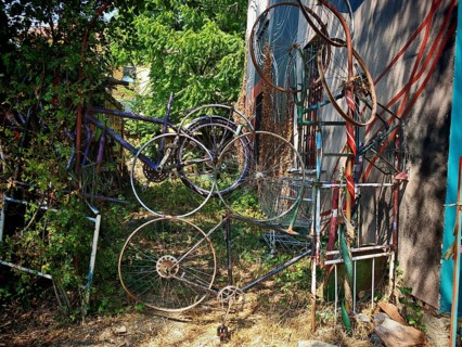 Old bicycle parts creatively arranged on a wall with trees and vegetation, Ljubljana, Slovenia