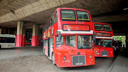 Classic red double-decker bus under a large concrete shelter at a bus station, Skopje, North
