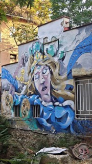 Wall art of a mythical woman surrounded by vivid colors and details, Pristina, Kosovo