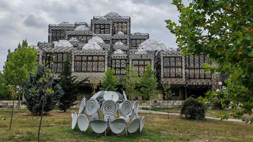 Architecturally distinctive building with domes and surrounding nature, National Library, Pristina,