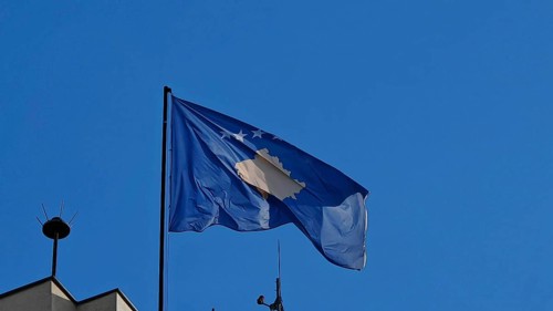 Close-up of a waving Kosovo flag against a clear blue sky, Pristina, Kosovo