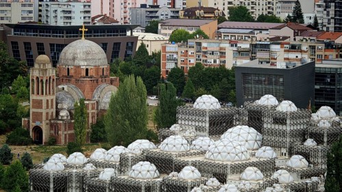 Church next to modern building with distinctive domes, National Library, Pristina, Kosovo