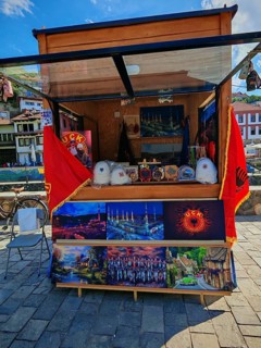 A sales stand with KLA souvenirs and flags under a blue sky, Prizren, Kosovo