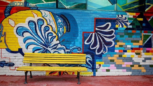 Colourful wall painting with geometric patterns and a yellow bench in the foreground, Skopje, North