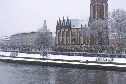 A passerby walks along the banks of the Main with an umbrella. Heavy snowfalls have caused another