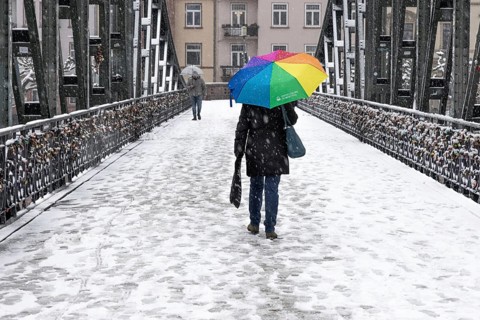A passer-by walks across the Iron Bridge in Frankfurt am Main with an umbrella. Heavy snowfalls
