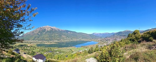 Wide view over a lake and mountains under a clear blue sky, view from above over Lake Plav,