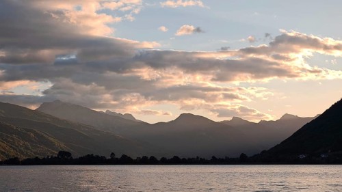 View across a lake to mountain silhouettes in warm sunset light, Plav Lake, Montenegro