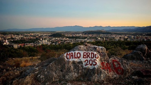 Panoramic view of a city in evening light with surrounding mountains and painted rock in the