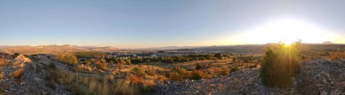 A city surrounded by nature with trees in the foreground and mountains in the background,