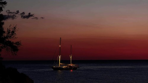 A sailboat at sunset on calm water surrounded by an atmospheric dusk, Ulcinj, Montenegro