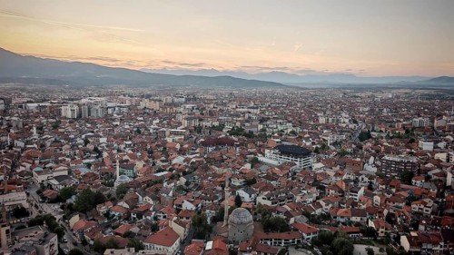 Extensive view of the city in evening light with mosque and mountains on the horizon, Prizren,