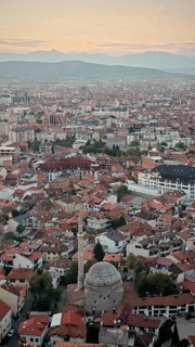 Wide view of a city at sunset with a distinctive mosque and red roofs, Prizren, Kosovo
