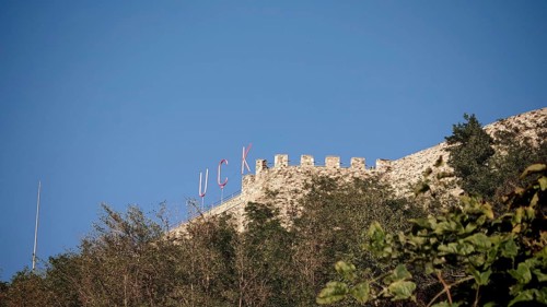 KLA lettering on an old castle on a hill with trees and blue sky, Prizren, Kosovo