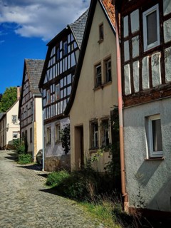 Painted village street lined with old half-timbered houses under a blue sky, Upper Franconia