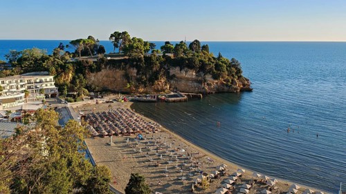 Sunny beach area with umbrellas and clear, blue sea on the coast, Montenegro