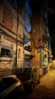 Night view of a city street with parked cars and worn buildings, Tirana, Albania