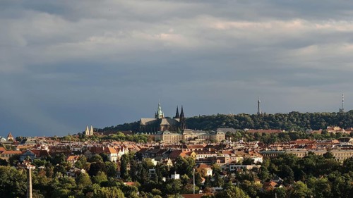 Panoramic view of a city with historic buildings under a cloudy sky, Prague