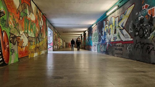 Long tunnel with colorful graffiti on the walls, some people can be seen in the background, Prague,