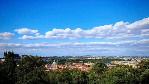 City panorama with distinctive buildings and green hills under a blue sky, view over Prague, Czech