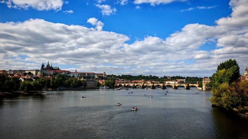 Boats on a river, a bridge and historic buildings under a cloudy sky, Prague, Czech Republic