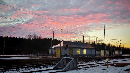 A small train station at dawn under a colorful sky with snow-covered ground, Rennsteig, Frankenwald