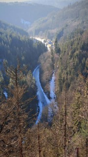 View of a winding road in the valley surrounded by wooded hills, Franconian Forest nature park Park