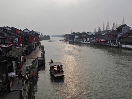 A leisurely evening view across the canal with traditional buildings and boat traffic, Zhujiajiao