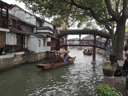 Traditional bridge over a canal with boats flanked by old houses and trees, Zhujiajiao Ancient