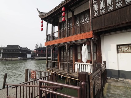 A traditional wooden house with red lanterns on the riverbank in a peaceful setting, Zhujiajiao