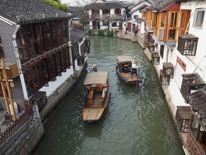 Two boats sail through a narrow canal lined with traditional Chinese buildings, Zhujiajiao Ancient