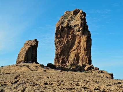 Two huge rock formations under a blue sky with people in the distance, Roque Nublo, Gran Canaria,