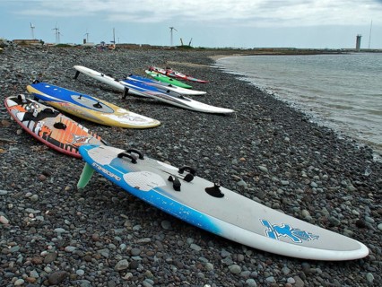 Pebble beach with colorful surfboards at sea under cloudy sky, Pozo Izquierdo, Gran Canaria, Canary