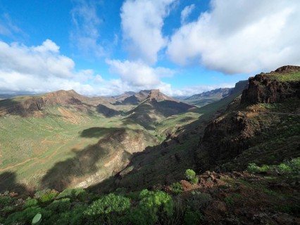 Wide mountain landscape with green valleys and dramatic cloudy sky, Barranco de Fataga, Gran