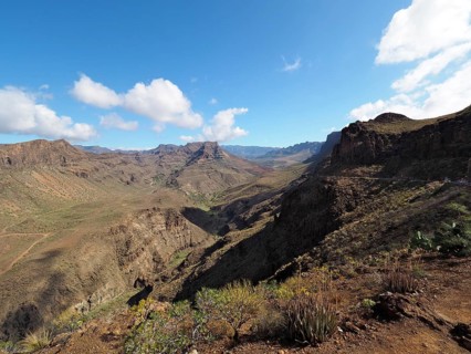 Arid mountain landscape with rocks and wide valley under a blue sky with clouds, Barranco de