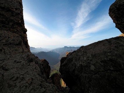 View through rocks of a vast mountain landscape under clear sky, Roque Nublo, Gran Canaria, Canary