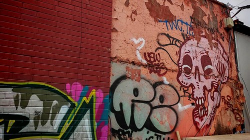 Colourful graffiti on an old wall with a skull motif and various lettering in an urban environment,