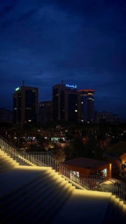Nighttime city view with illuminated buildings and illuminated staircases in the foreground,