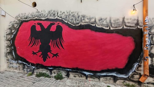 Graffiti depicting the flag of Albania with a black eagle on a red background on a wall along a