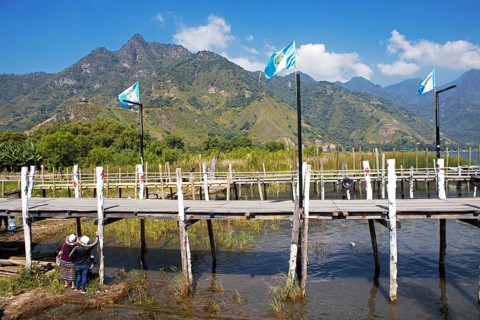 Guatemalan people wearing traditional clothing on a wooden pier in the port of San Juan la Laguna,