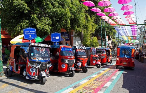 Red tuk tuks or tricycle taxis in an alley in San Juan la Laguna, Atitlán, Sololá Department,