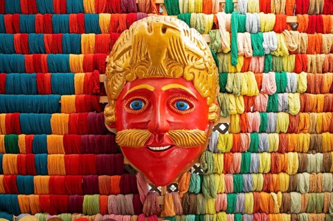 Mask of a Moro or Moor for traditional mask dance, behind a wall full of colorful cotton,