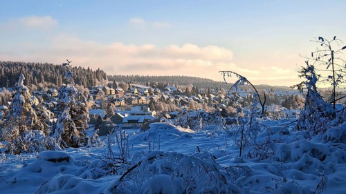 Winter village in snowy landscape with hills and forests in the evening light, Rennsteig,