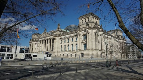 Side view of the Reichstag with flags under a blue sky, deserted during Corona, Berlin