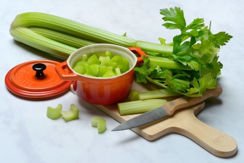 Celery stalks, pieces in pots with kitchen knife