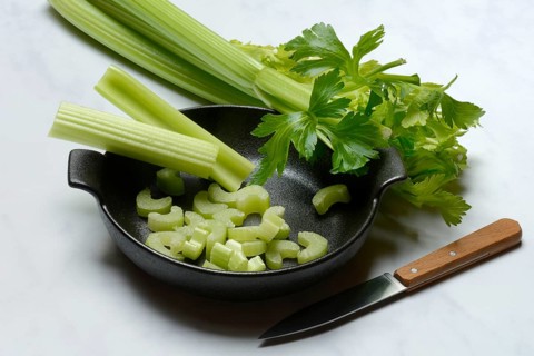 Celery stalks, pieces with knife in pot