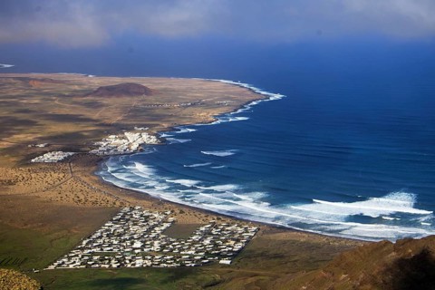 Wide coastline with bright waves and the seaside village of Caleta de Famara by the sea, Mirador de