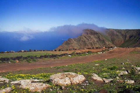 A narrow path high up in the mountains of the Famara massif with views of the sea with clouds in